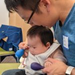 Dad and baby use shakers during a Hatchlings program.