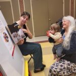 A baby joyfully experiences a picture book at a session in Kent County, MD.